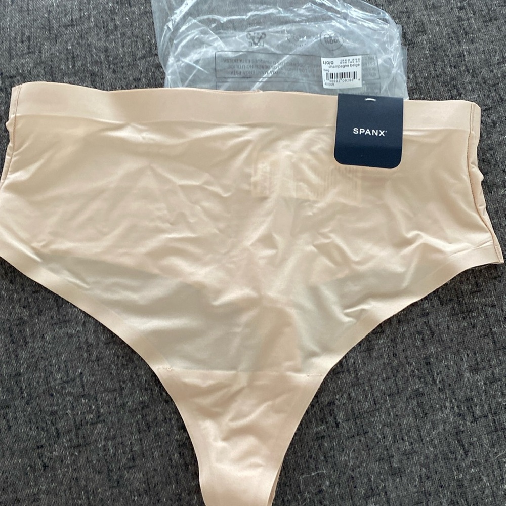 New with tags Spanxshape sheer control thong in champagne beige, size large.